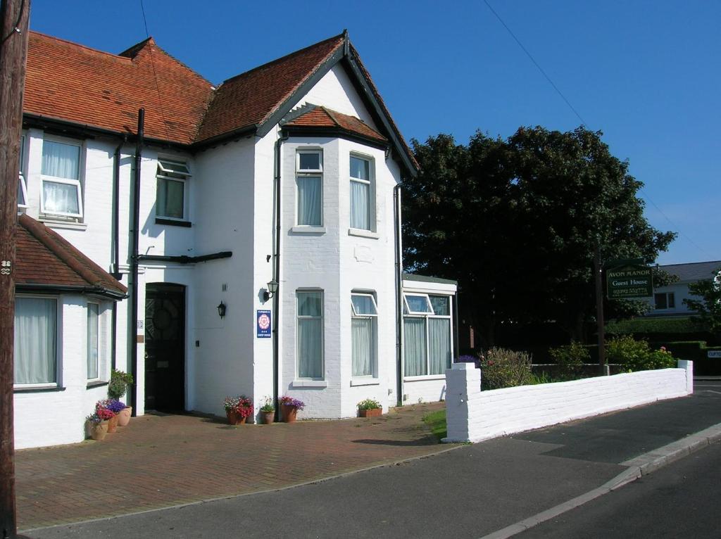 索伦特海峡旁利村Avon Manor Guest House的街上有红色屋顶的白色房子