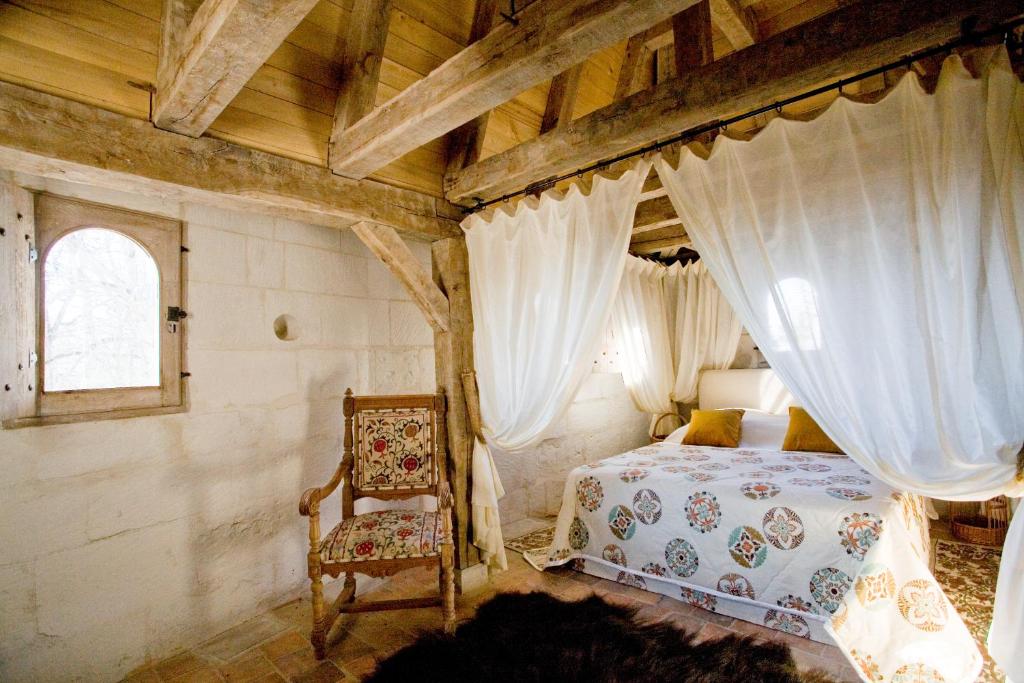 莱梅雷Hôtel du Château du Rivau的一间卧室配有一张天蓬床和一把椅子