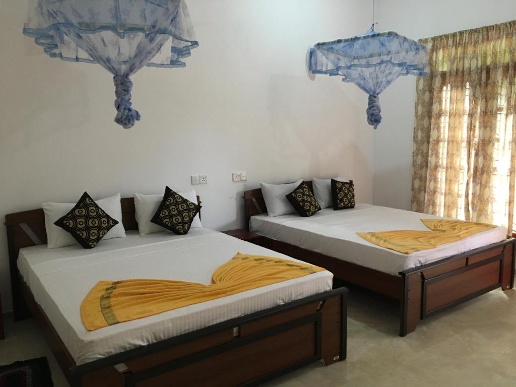 锡吉里亚Sigiri Rangana Guesthouse的两张睡床彼此相邻,位于一个房间里