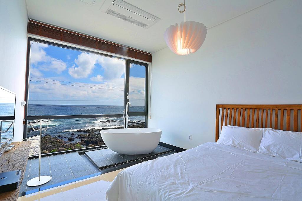 西归浦市The Villas Ocean for Family的卧室设有带浴缸的大窗户