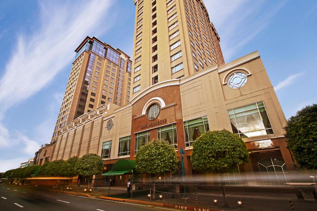 马尼拉The Bellevue Manila的一座大型建筑,上面有钟,有两座高楼
