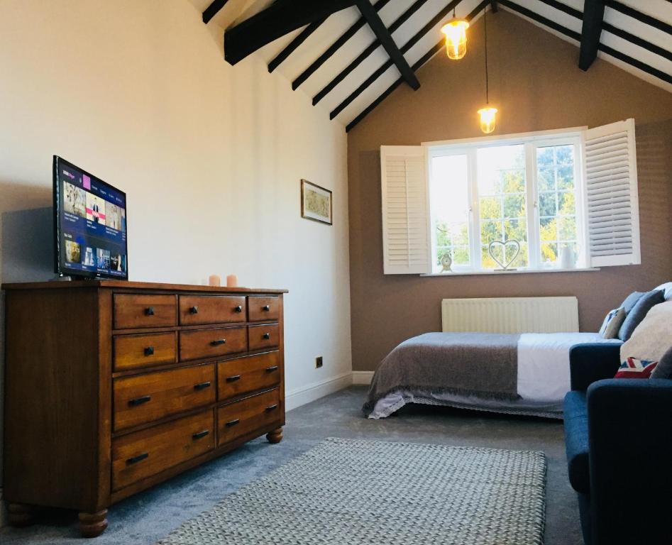 凯尼尔沃思Kenilworth Cosy Garden View Apartment的一间卧室配有一张床和一个带电视的梳妆台
