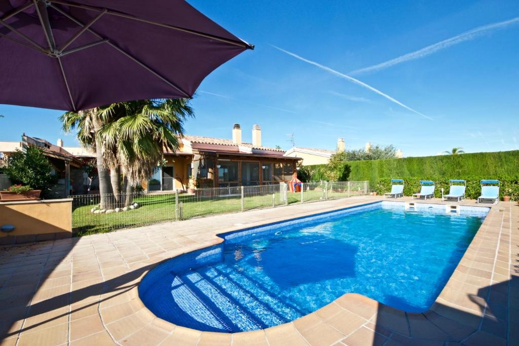 安波拉Villa Alegría的一座房子旁带遮阳伞的游泳池