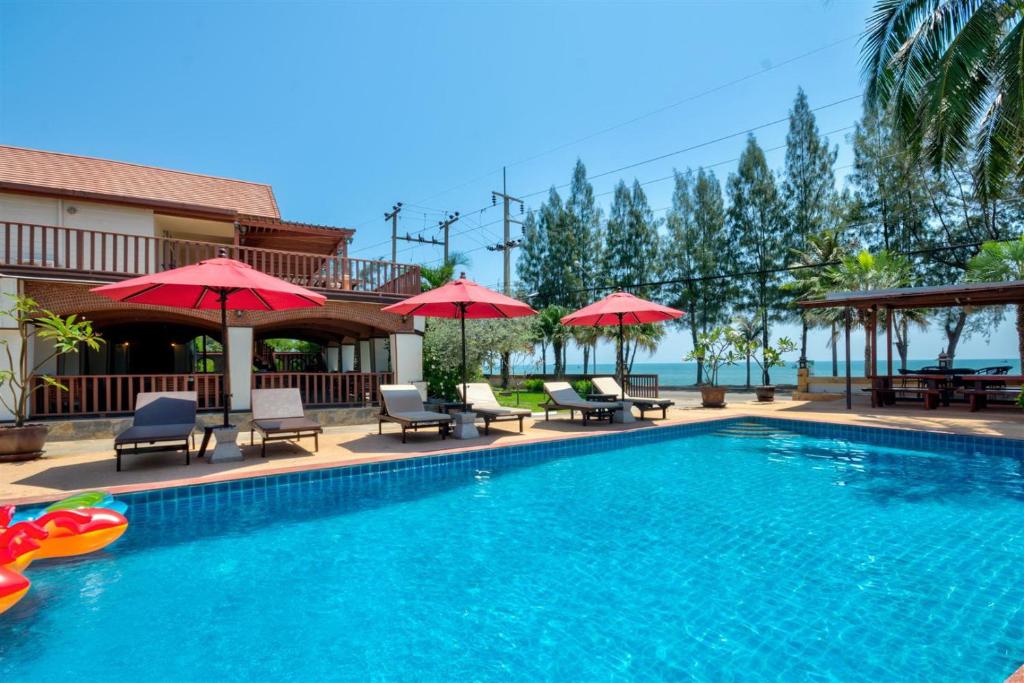 盼武里棕榈海滩度假村的一个带椅子和遮阳伞的游泳池