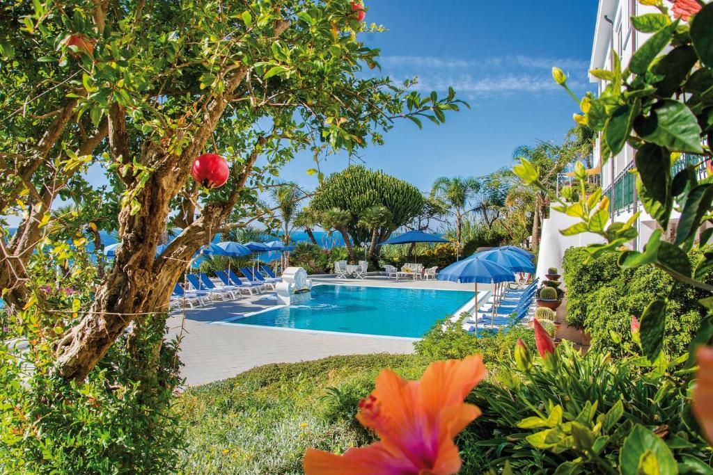 伊斯基亚卡皮佐酒店的度假村的游泳池,配有椅子和遮阳伞