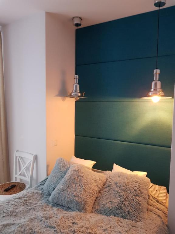 加茨比亚格拉Amko Style Apartamenty Róża Wiatrów Willa Nord的一间卧室配有一张带绿色床头板和灯的床。