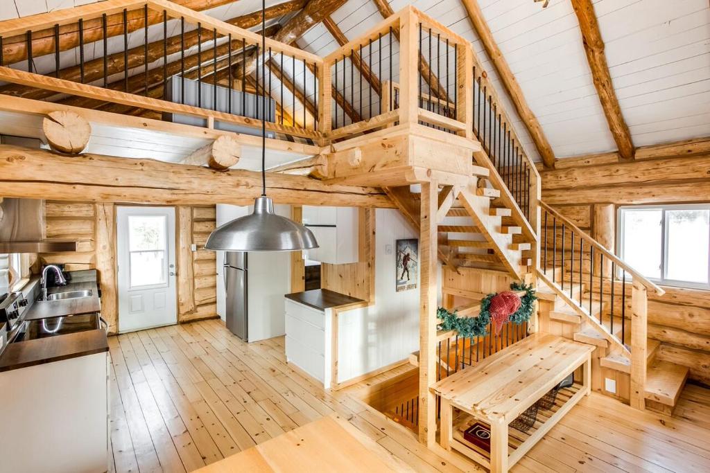 Saint Adolphe D'HowardLe log home - Locations du sommet的小木屋内的厨房和客厅设有螺旋楼梯