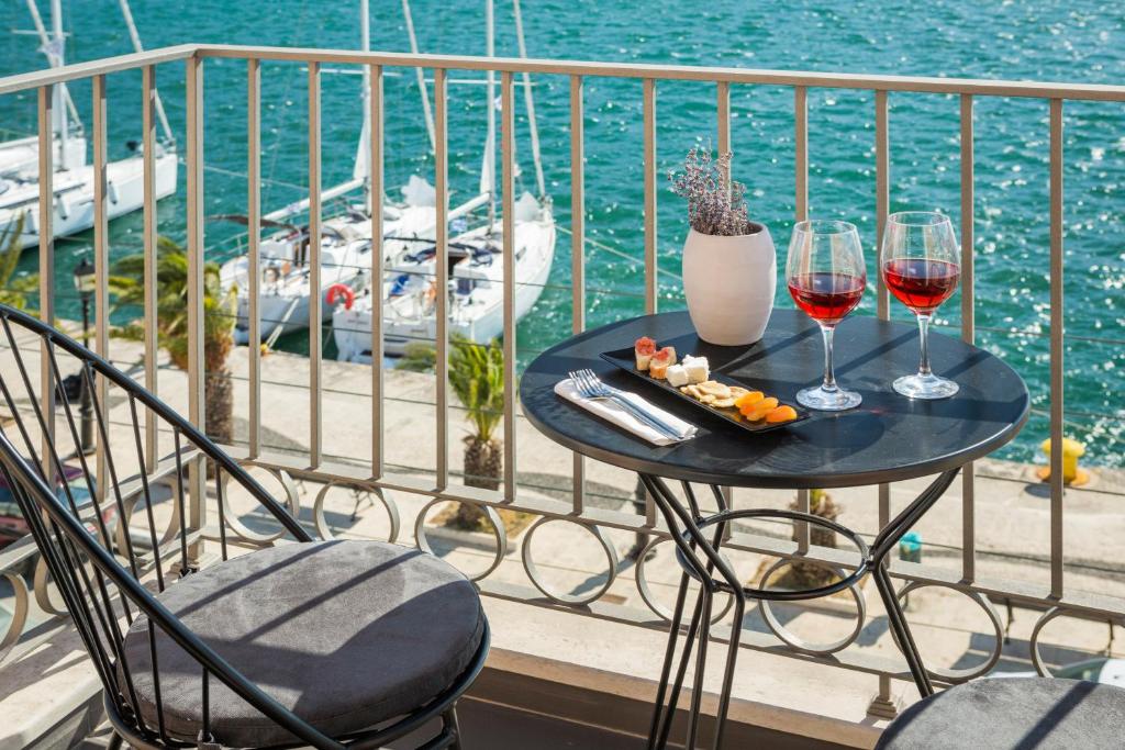 阿尔戈斯托利翁Argostoli Marina Suites的一张桌子,上面放着两杯葡萄酒和一盘食物