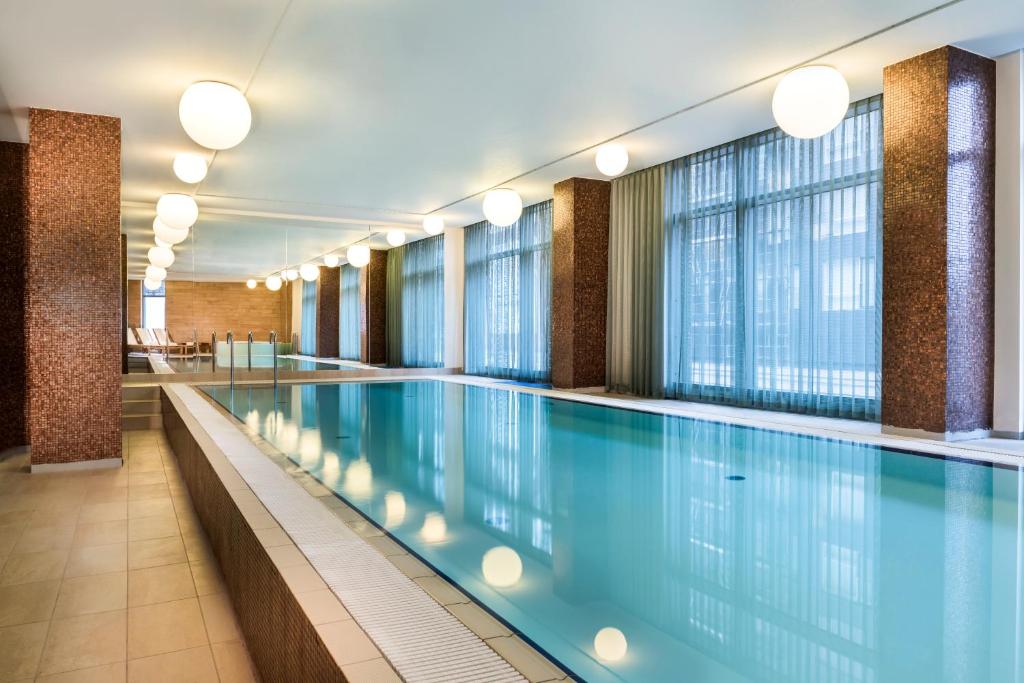 哥本哈根哥本哈根阿迪娜公寓式酒店的一座大型游泳池,位于一座带窗户的建筑内