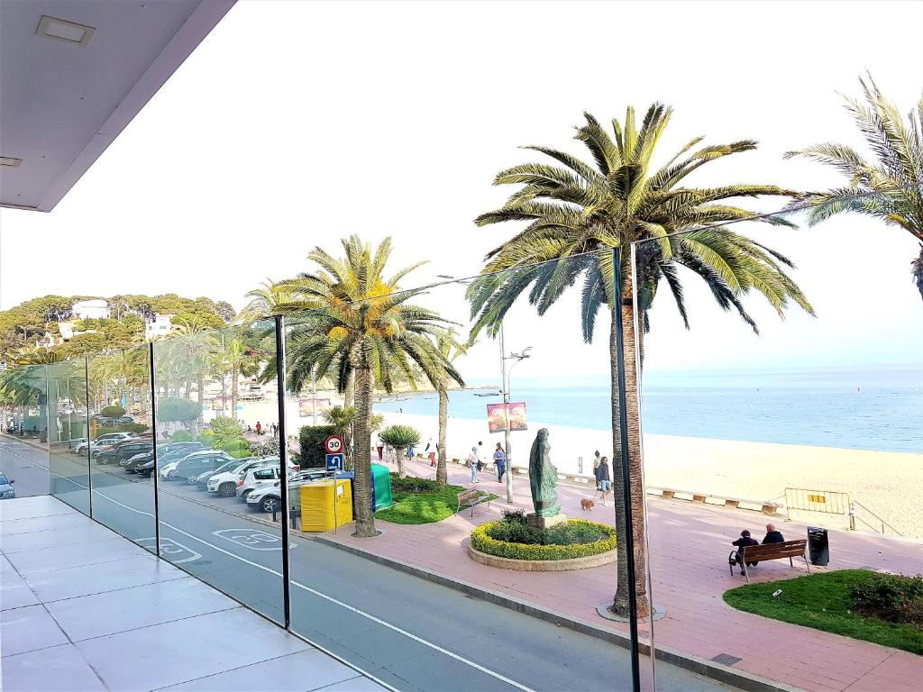 罗列特海岸Lloret Paradise Apartments的享有棕榈树街道和海滩的景色