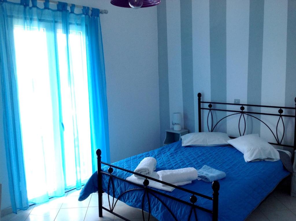 利瓦迪奥ELEFTHERIA rooms的一间卧室配有一张蓝色墙壁的床和一扇窗户
