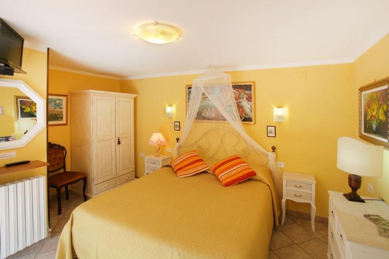 圣吉米纳诺普利美特豪斯酒店的黄色卧室配有带橙色枕头的大床