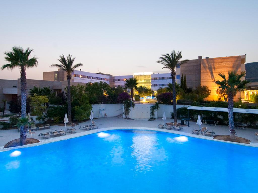 曼弗雷多尼亚曼弗雷迪瑞金酒店的一座种植了棕榈树和建筑的大型蓝色游泳池