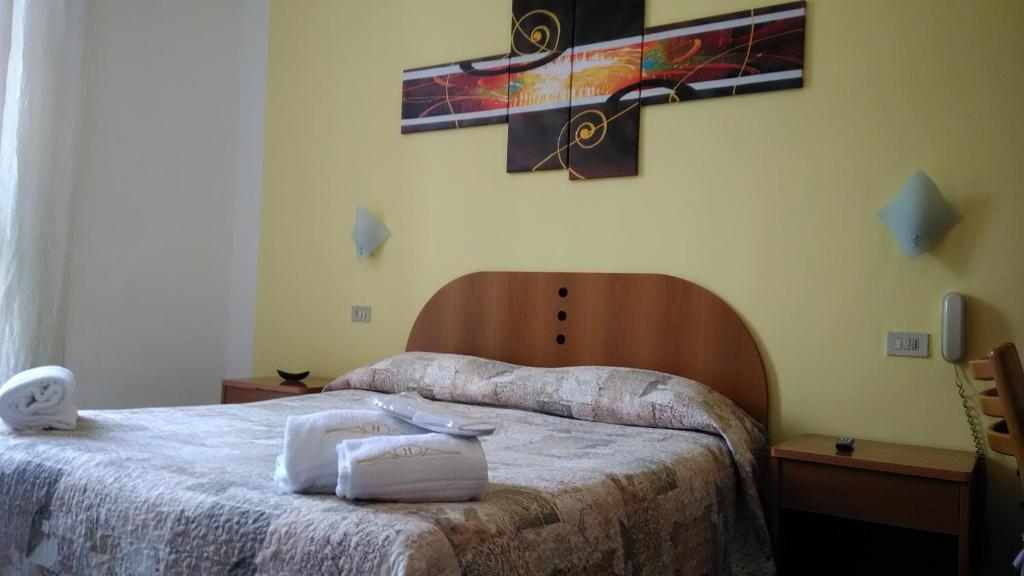 米兰Hotel Tirreno的卧室配有两张床,墙上有一个十字架