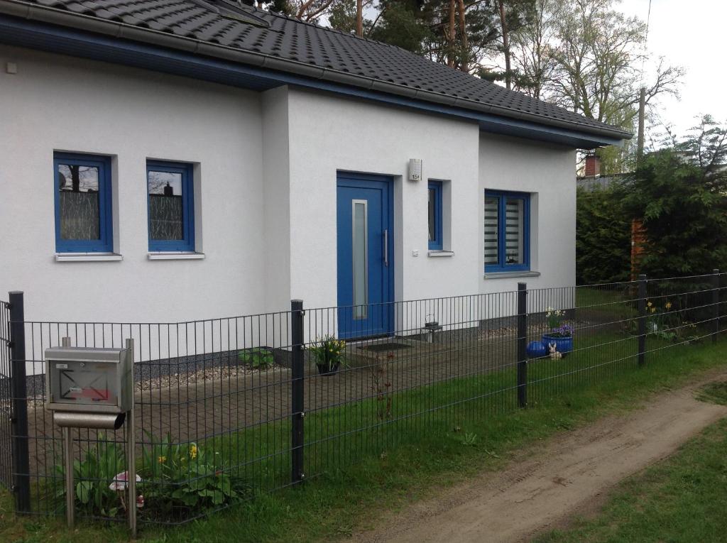 格拉尔-米里茨Klünnersnest Graal Müritz的白色的房子,设有蓝色的窗户和栅栏