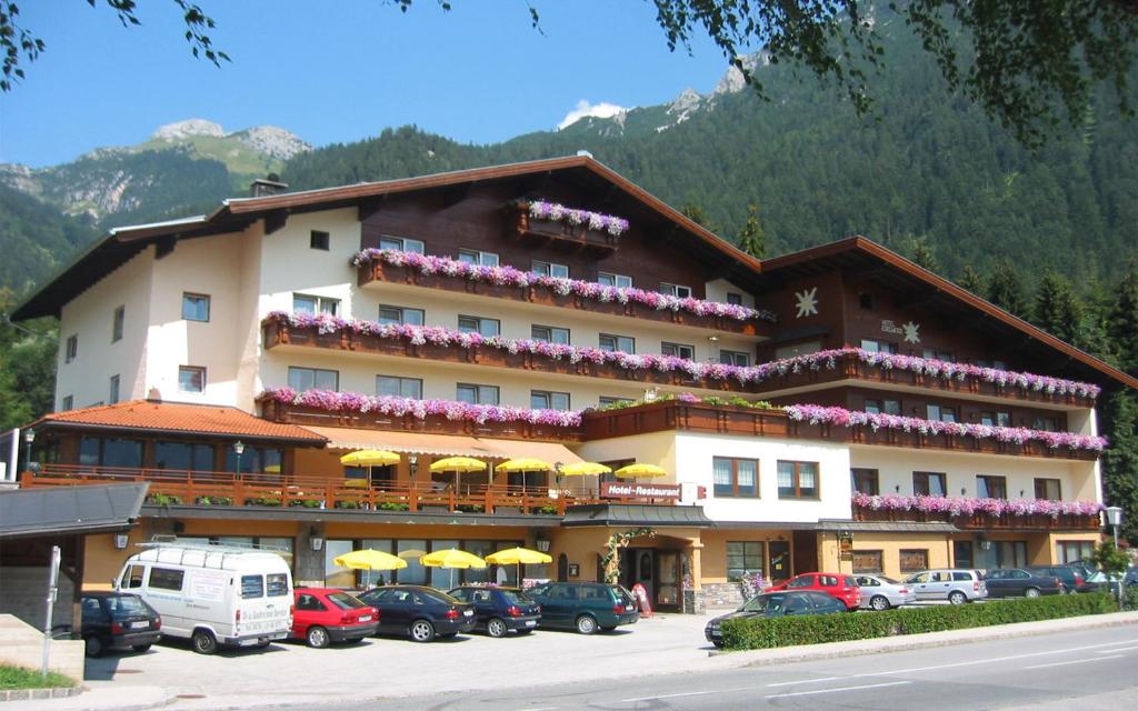 毛拉赫Alpenhotel Edelweiss的大型酒店,停车场内有车辆停放