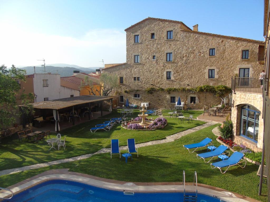 帕拉莫斯Hotel Sant Joan的享有带游泳池的大型石头建筑的外部景色