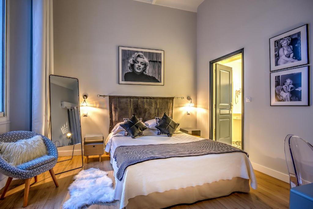 戛纳Villa Claudia Hotel Cannes Centre - Parking的一间卧室配有一张床、一把椅子和镜子