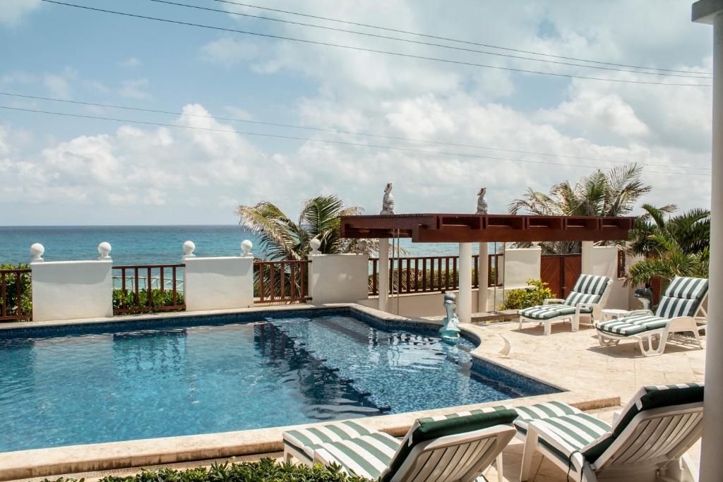 女人岛Villa Isla Dorada的一个带椅子的游泳池,背景是大海