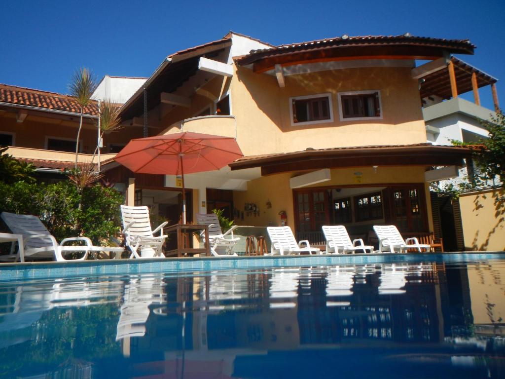 马利西亚斯Pousada Mosaico Brasil - Maresias的一座房子,设有游泳池、椅子和遮阳伞