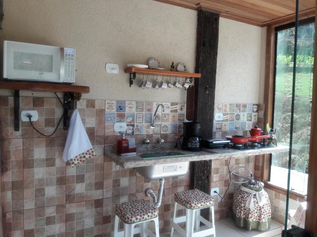 圣安东尼奥-杜皮尼亚尔Pousada Cores e Flores da Serra的厨房配有水槽和带凳子的台面