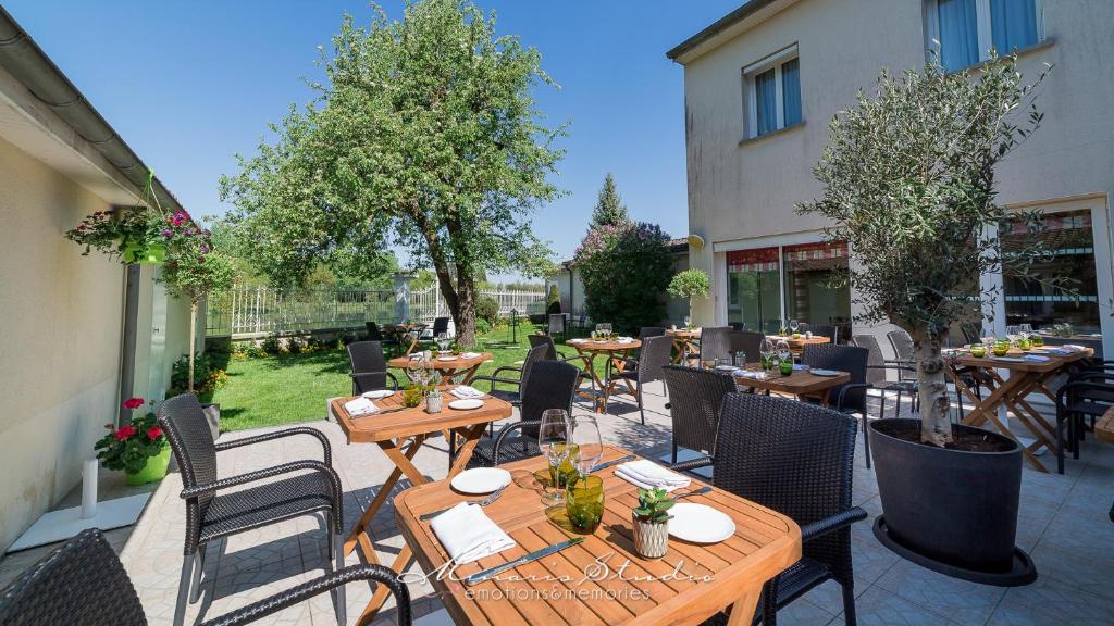 塞纳河畔诺让贝瑞瓦之酒店的户外庭院配有桌椅和树木。