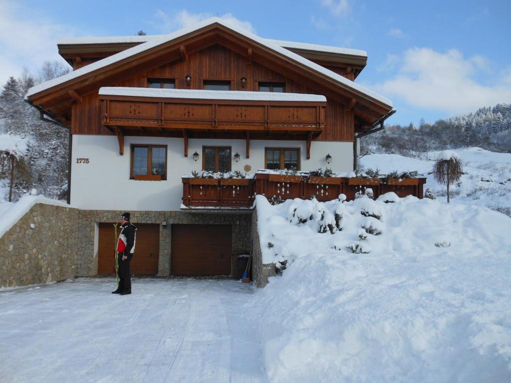 奥什恰德尼察马格斯公寓旅馆的站在房子前的雪中的一个男人