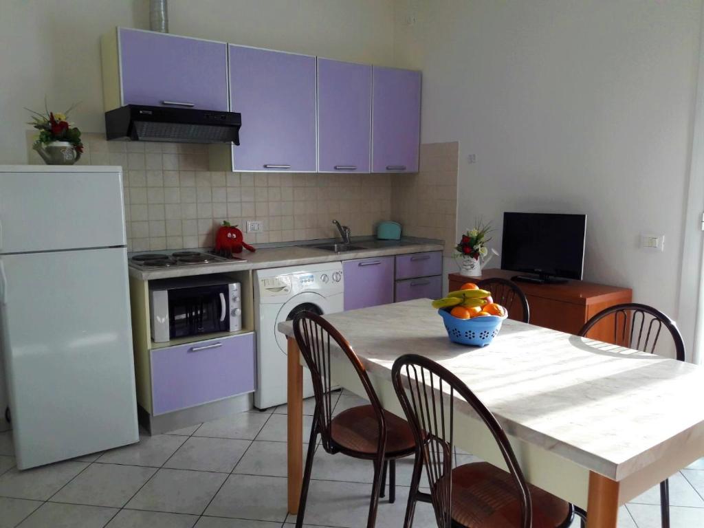 切尔维亚Residence Onda Blu的厨房配有紫色橱柜和桌椅