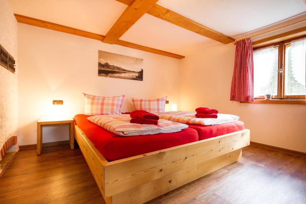 奥伯斯特多夫Cafe Christlessee的一间卧室配有一张铺有红色床单的木床。