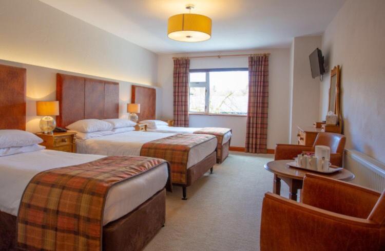康镇Lydons Lodge Hotel的酒店客房设有两张床和一张桌子。