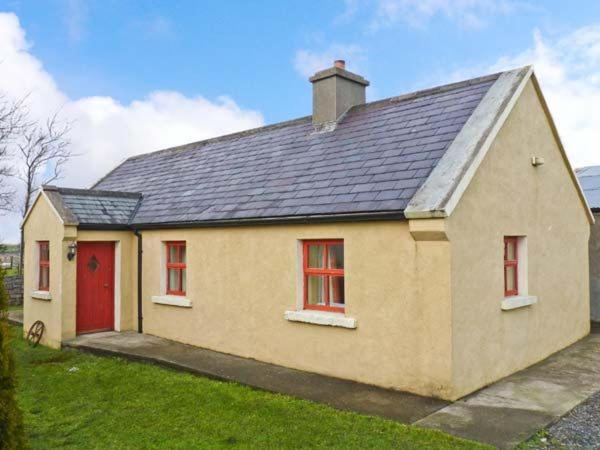 巴林罗布Cavan Hill Cottage的一间黄色的小房子,有红色的门