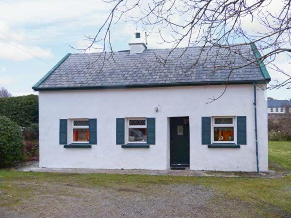 KnockThe Lake House, Connemara的白色的房子,设有绿色的窗户和门