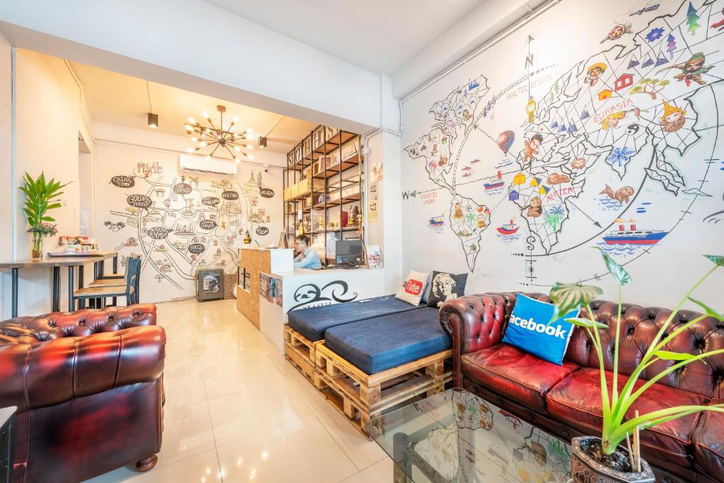 曼谷Sloth Hostel Khaosan的客厅配有皮革家具和壁画