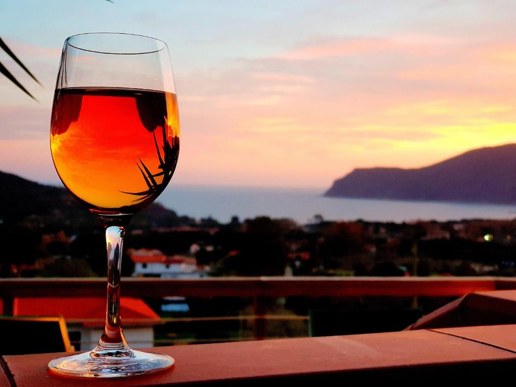 拉科纳Mini Appartamenti Elba的坐在桌子上一边欣赏日落,一边品尝葡萄酒