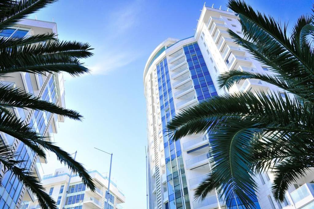 布德瓦Apartments Menuet的一座高大的建筑,前面有棕榈树