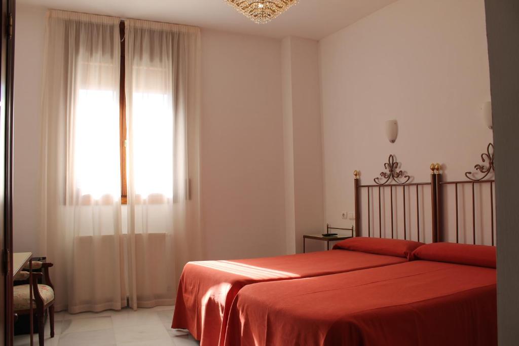科尔多瓦唐宝拉酒店的一间卧室配有一张带红色毯子的床和窗户。