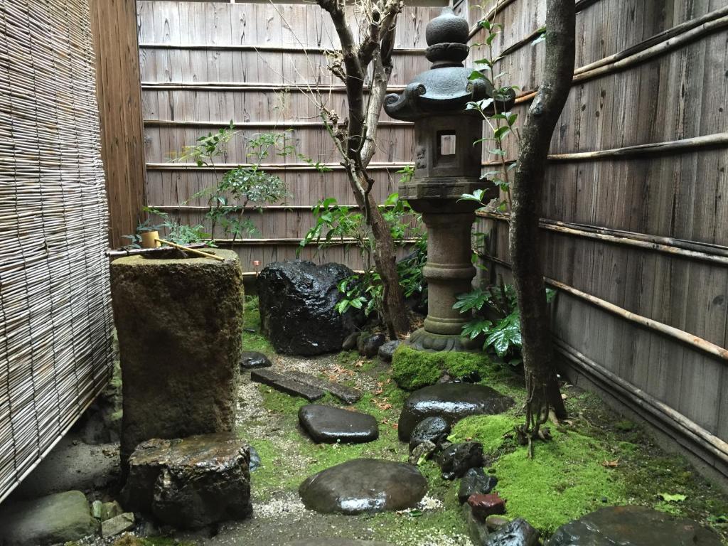 京都希促间旅馆的花园设有鸟浴缸和围栏