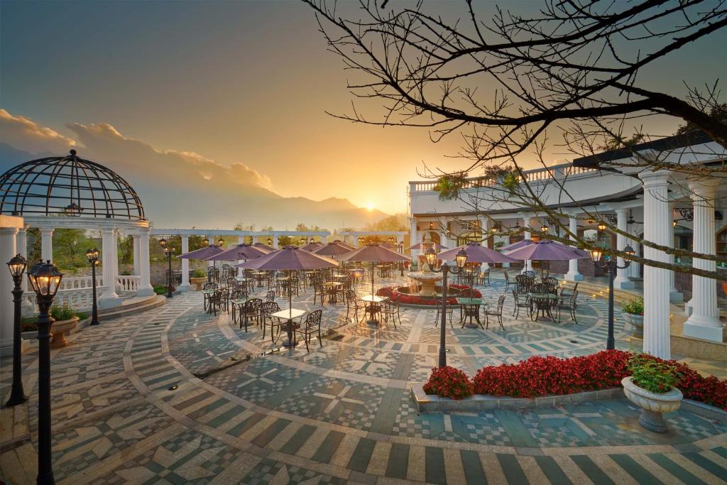 萨帕Silk Path Grand Sapa Resort & Spa的庭院的 ⁇ 染,庭院里摆放着桌子和遮阳伞