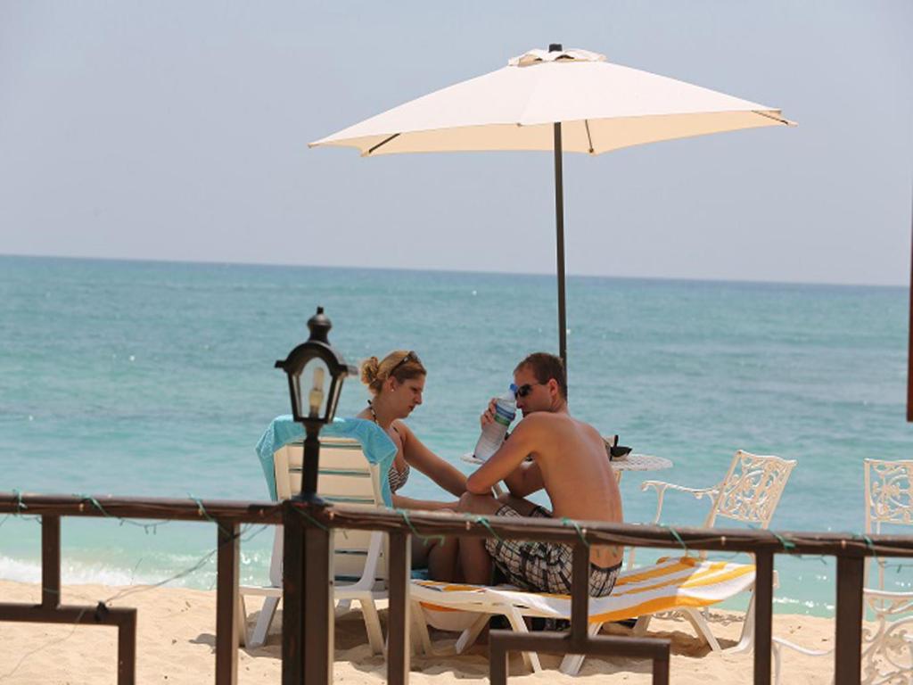 乌纳瓦图纳别墅酒店 的坐在海滩上的男人和女人