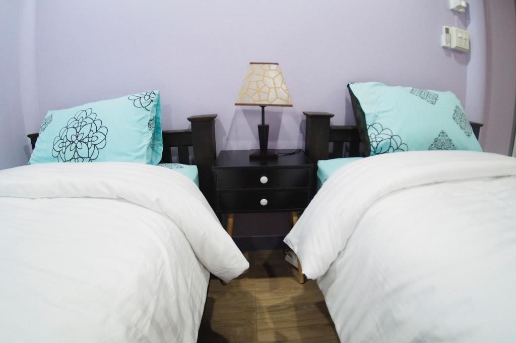 大城Pan Din Boutique Guest House的一间卧室配有两张床和一张带台灯的桌子