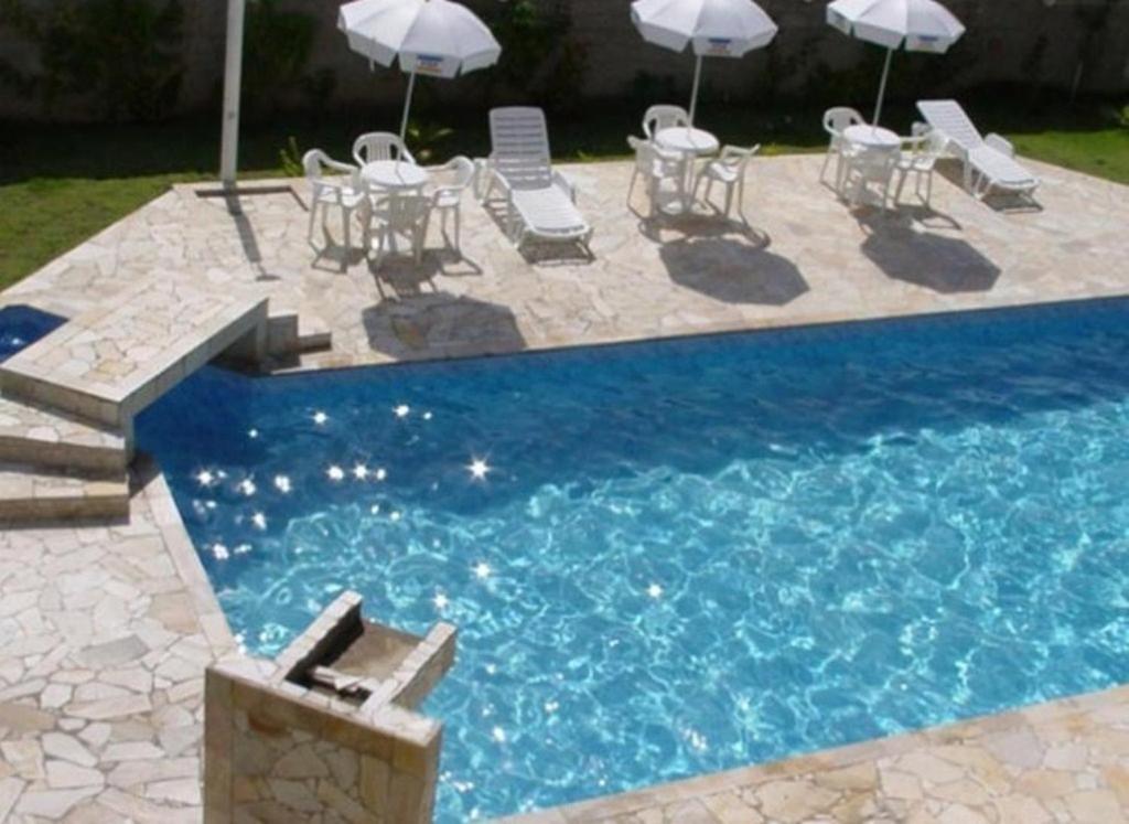 巴雷克萨巴Hotel Portal de Barequeçaba的庭院内一个带桌椅和遮阳伞的游泳池