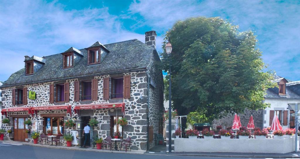 Saint-Martin-sous-VigourouxHotel De La Poste的街道上红色点缀的石头建筑