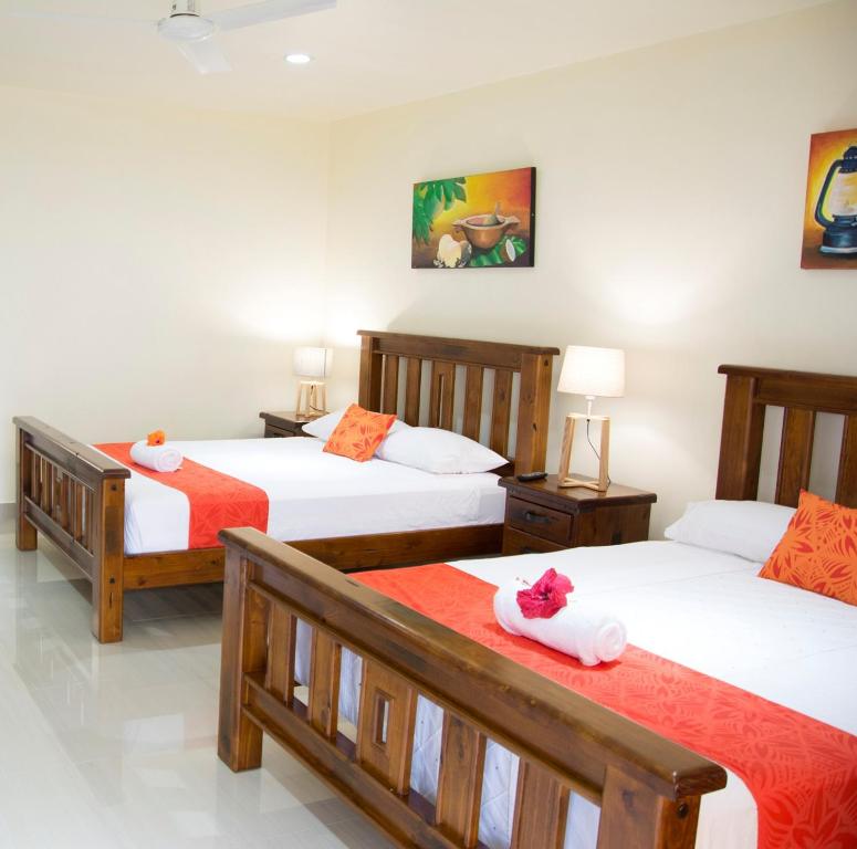 阿皮亚Samoana Boutique Hotel的一间卧室配有3张床,提供橙色和白色床单