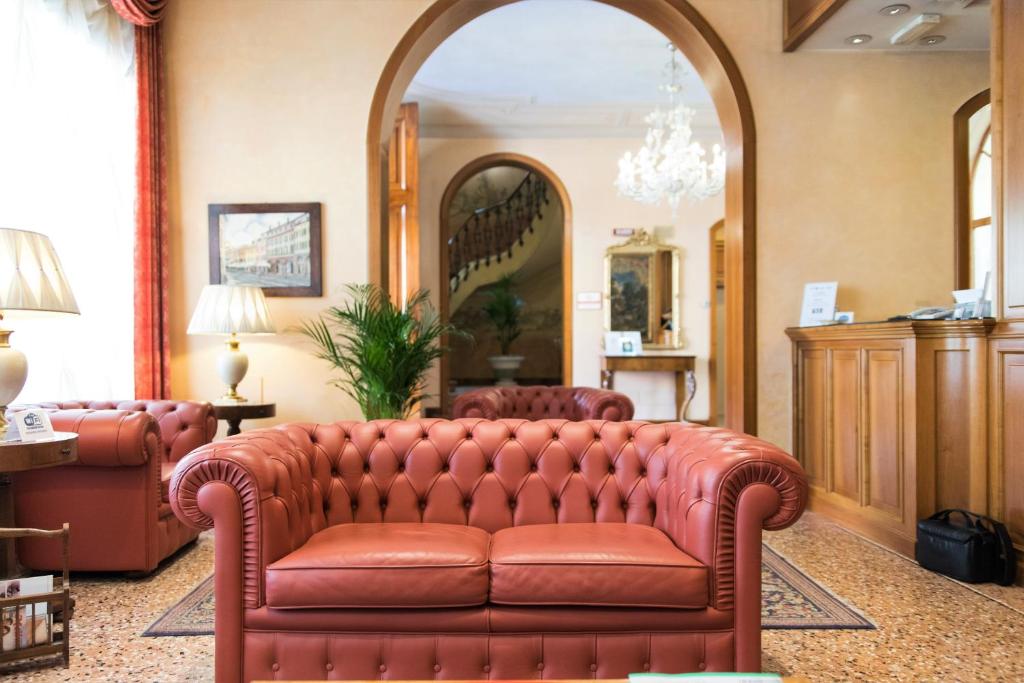 科雷焦Phi Hotel Dei Medaglioni的客厅配有皮沙发及镜子