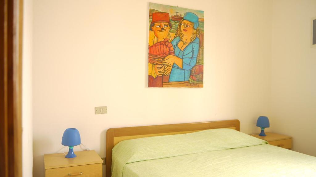 莱乌卡Residence Trande的卧室配有一张床,墙上挂有绘画作品