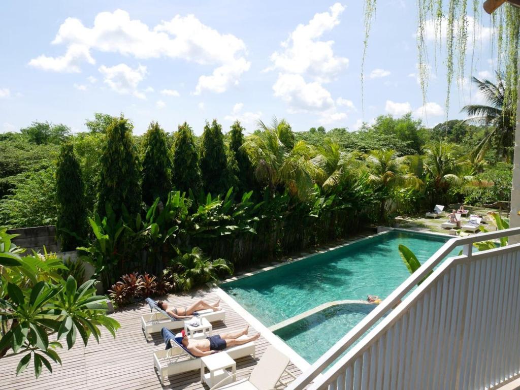 乌鲁瓦图巴东巴东酒店的一座游泳池,可供两人躺在度假村的椅子上