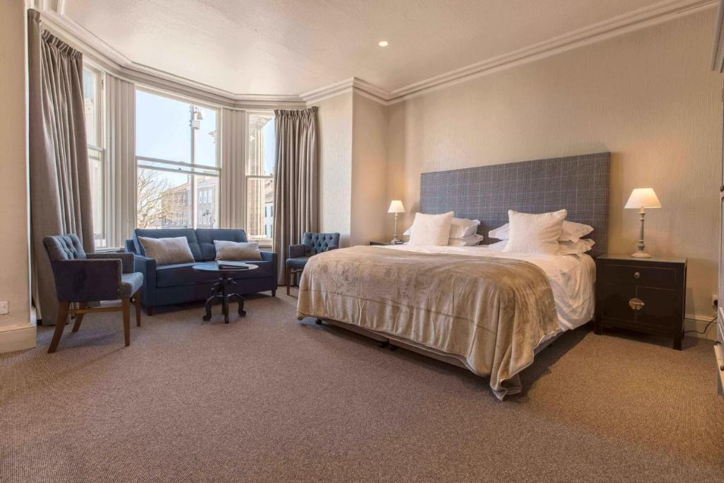 卡斯尔敦乔治酒店的一间卧室配有一张床、一张沙发和一把椅子