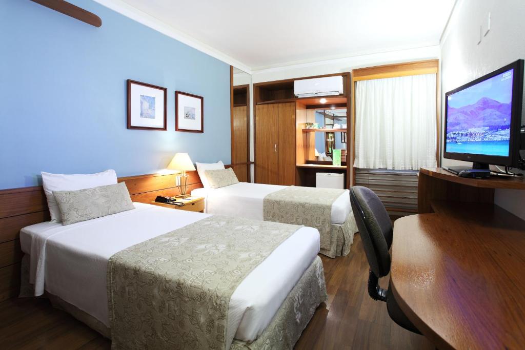 普雷图河畔圣若泽Hotel Dan Inn São José do Rio Preto的酒店客房设有两张床和一台平面电视。
