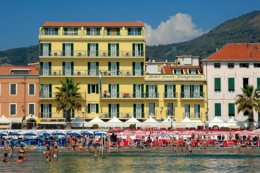 阿拉西奥Hotel Danio Lungomare的一群人,在海滩上,在一座黄色建筑前