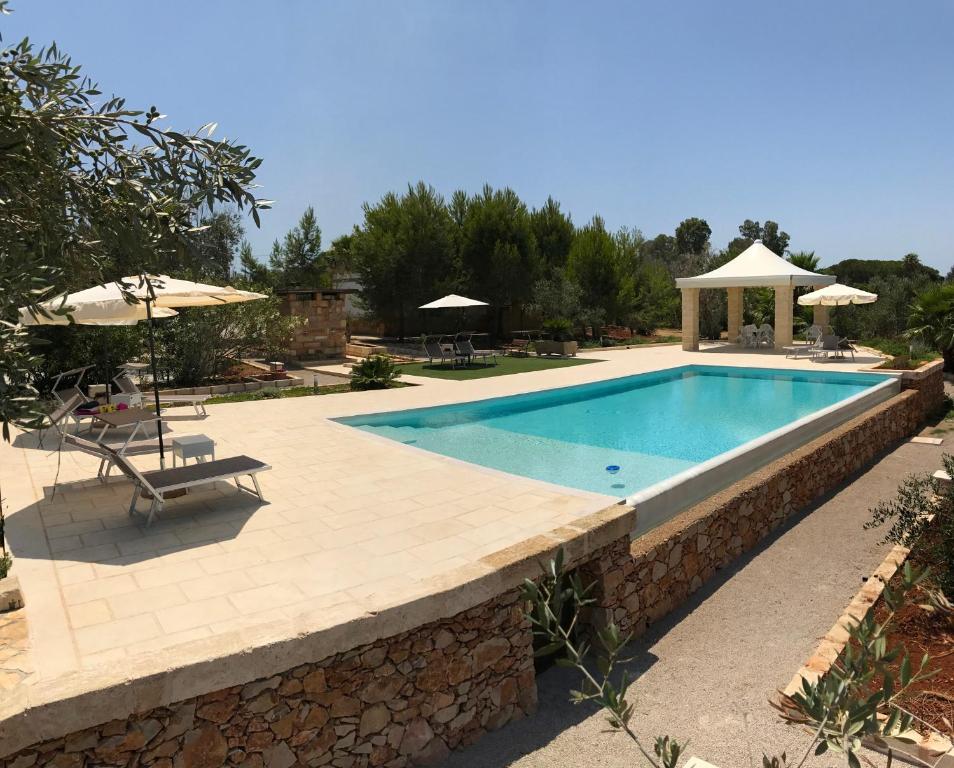 马蒂诺WHITE POOL Matino - Gallipoli - 7pl的度假村内的游泳池,配有桌子和遮阳伞